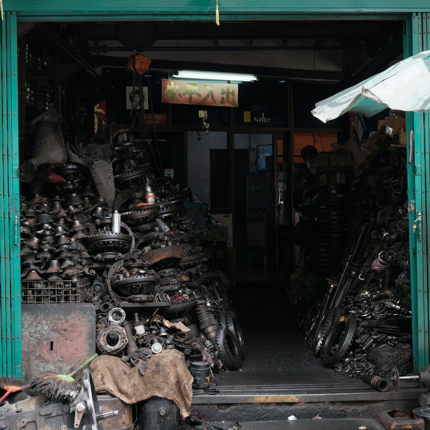 Rommelige garage met stapels motoronderdelen.