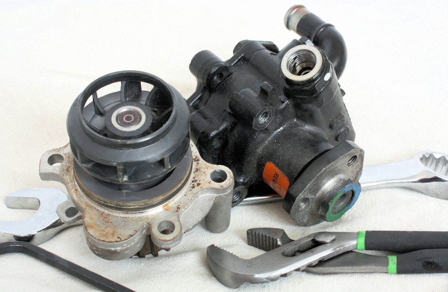 Diverse auto-onderdelen en gereedschap op een witte ondergrond.